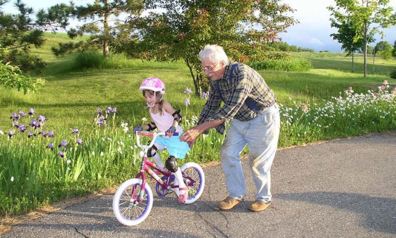 Grand-père aidant sa petite fille à faire du vélo